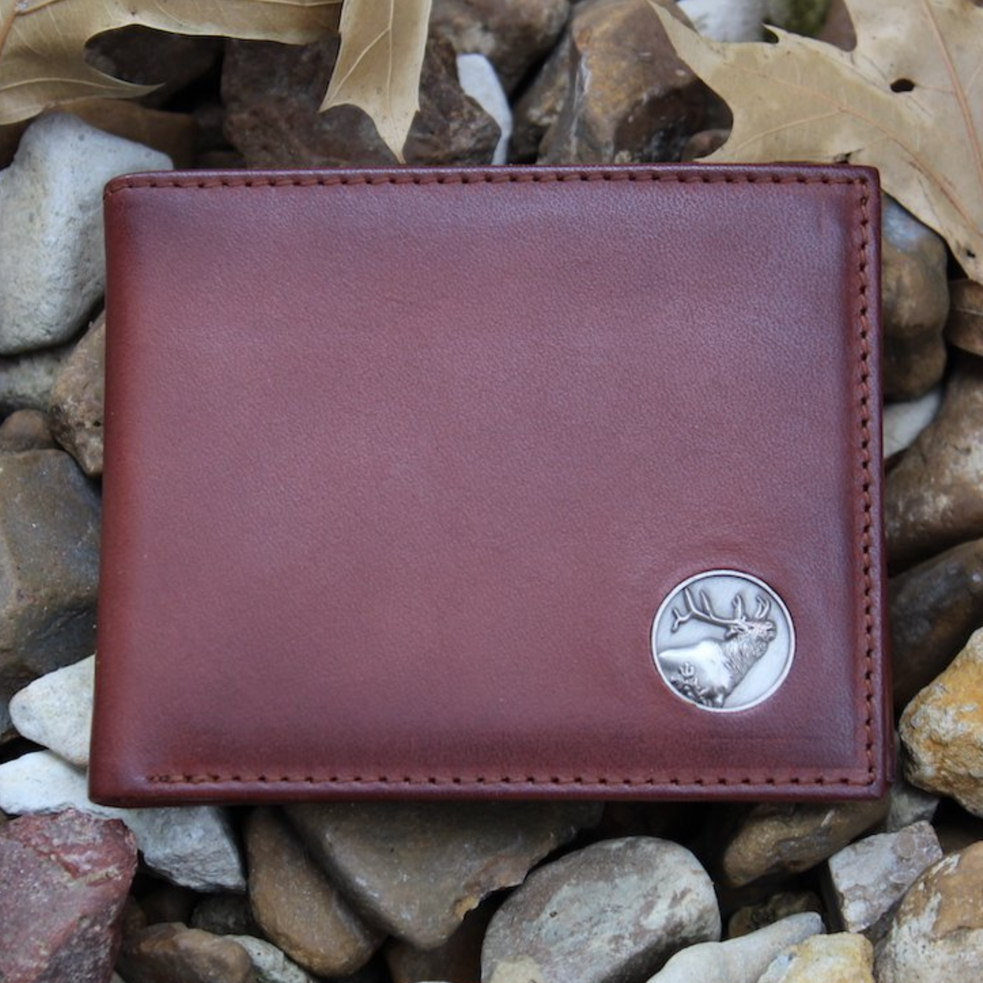 The Wildlife Bifold Elk Wallet is created from hand-burnished, rich full grain leather, providing a beautiful aged patina. The elk concho provides a personalized touch...stylish and unique, this piece is a must-have for any collection! 8 Card Slots 3 Storage Pockets 2 ID Windows Leather Tipped Bill Divider Weber's Signature Elk Concho Dimensions: 4.5"L x 3.5"H RFID Protection Color: Caramel